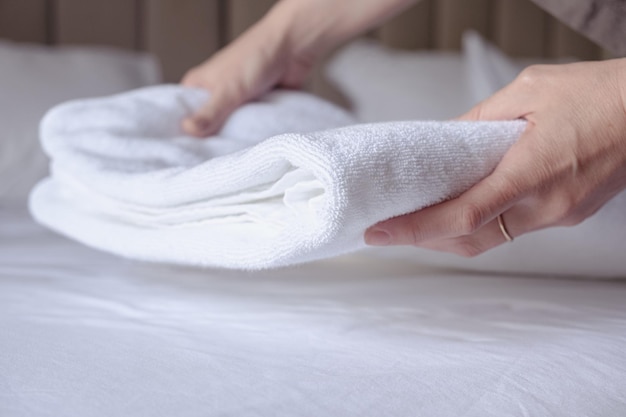 Ręce kobiety kładą na łóżku czysty biały ręcznik frotte