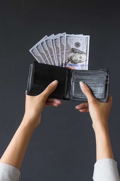 Ręce kobiety pokazujące setki dolarów na portfelu odizolowanym na szarym tle