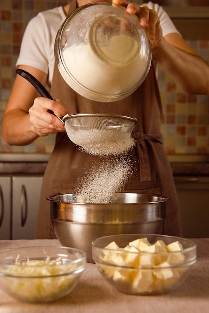 Zdjęcie ręce kobiety przesiewają mąkę przez sito nasycają mąkę powietrzem dla miękkiej tekstury ciasta