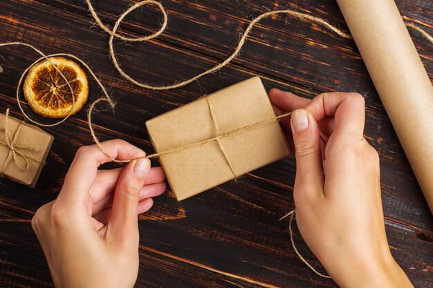 Ręce kobiety robiące prezent z papieru rzemieślniczego.