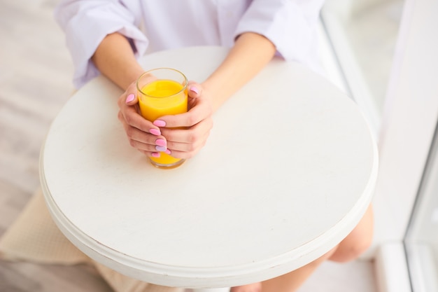 ręce kobiety trzymają szklankę soku pomarańczowego