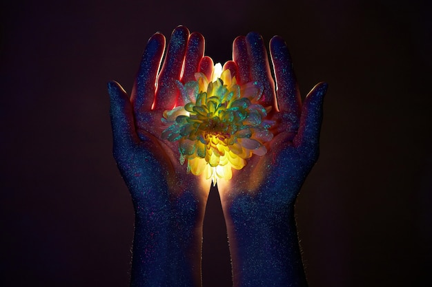 ręce kobiety w świetle ultrafioletowym z kwiatami na dłoniach