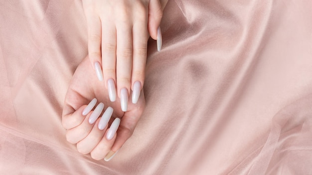 Ręce kobiety z manicure na paznokciach są pomalowane na biały kolor