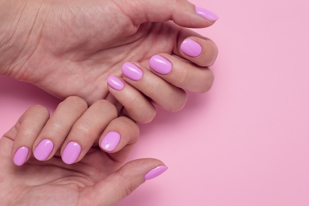 Ręce kobiety z różowym manicure.