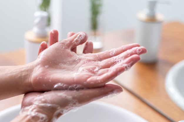 Ręce kobiety za pomocą mydła i mycie rąk pod bieżącą wodą