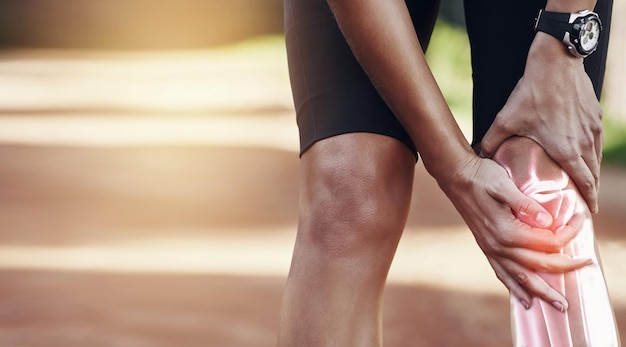 Ręce kolano i kontuzja u sportowca trzymającego staw w bólu po wypadku podczas biegania na świeżym powietrzu Ćwiczenia lub trening fitness oraz sportowiec zmagający się z kontuzją nogi