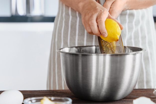 Ręce kucharza zetrą skórkę z cytryny do miski ciasta Naturalny aromat w skórce cytryny vidi Przygotowanie składników w kuchni piekarni lub restauracji