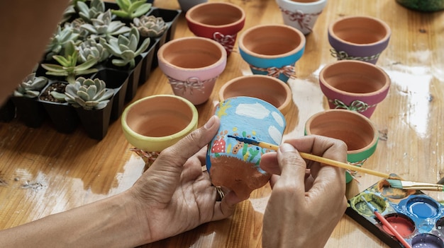 Ręce latynoskiej Mulatki malującej gliniane doniczki do sadzenia sukulentów