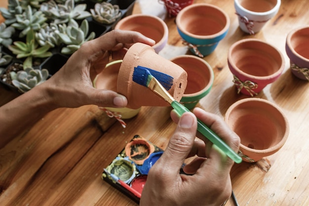 Ręce latynoskiej Mulatki malującej gliniane doniczki do sadzenia sukulentów
