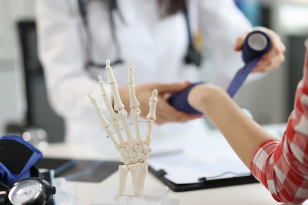 Ręce lekarza traumatologa bandażują kobiecą rękę