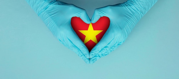 Ręce lekarzy w niebieskich rękawiczkach chirurgicznych, dzięki którym usłyszysz symbol kształtu z flagą wietnamu