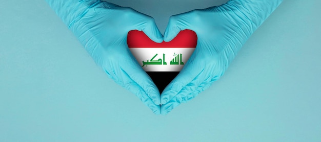 Ręce lekarzy w niebieskich rękawiczkach chirurgicznych, które sprawiają, że słyszysz symbol kształtu z flagą iraku