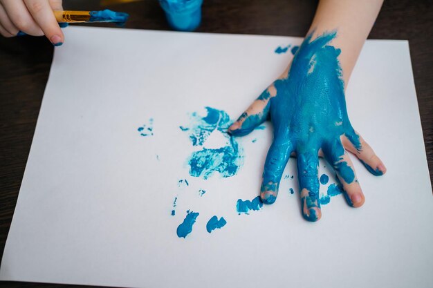 Zdjęcie ręce malowania mały chłopiec i stół dla kreatywności ręczne malowanie dzieci
