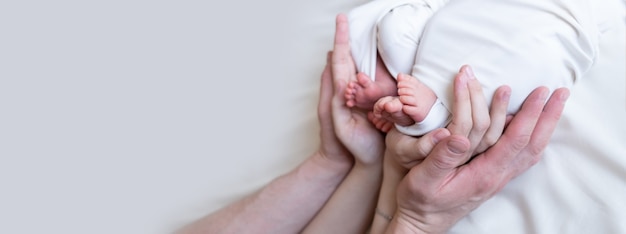 Ręce Mamy I Taty Trzymają Małe Nóżki Ich Dwojga Noworodków Bliźniaków. Zapłodnienie Pozaustrojowe. Ciąża Mnoga