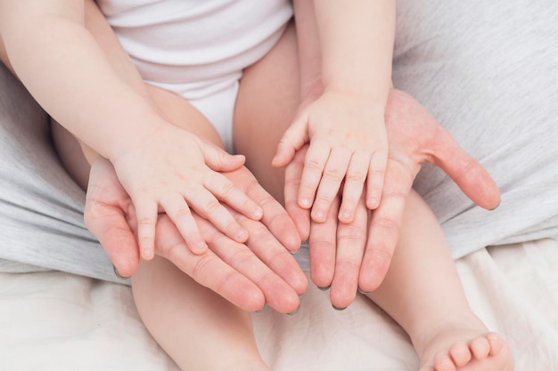 Ręce matki i małego dziecka zbliżenie jasne kolory Mama przytula dziecko Pojęcie macierzyńskiej miłości i opieki rodzicielskiej Tło na Dzień Matki i Dzień Dziecka