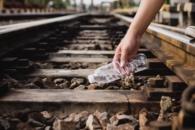 Ręce mężczyzn zbierają plastikowe śmieci na torach kolejowych