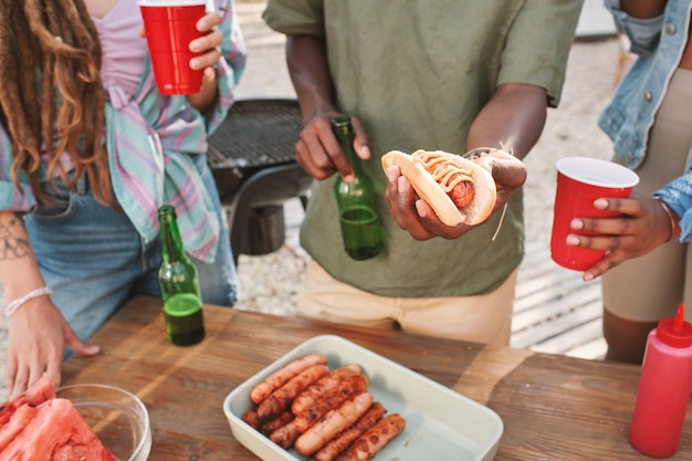 Ręce Mężczyzny Pijącego Piwo I Robiące Hot Dogi Dla Przyjaciół Na Imprezie Na Plaży