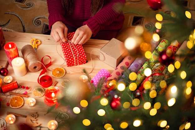 Zdjęcie ręce młodej kobiety przygotowującej prezenty świąteczne dla przyjaciół i krewnych