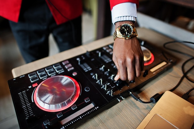 Ręce mody african american man model DJ w czerwonym garniturze z kontrolerem dj