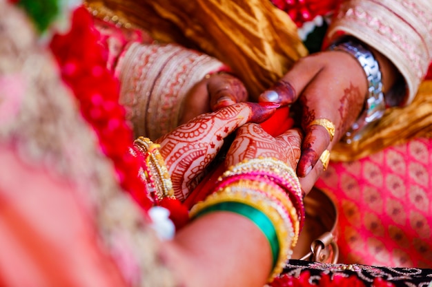 Ręce panny młodej są pięknie ozdobione indyjską sztuką mehndi wraz z biżuterią i kolorowymi bransoletkami
