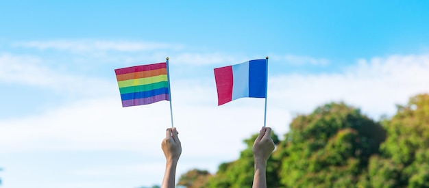 Ręce pokazujące flagę LGBTQ Rainbow i Francji na tle przyrody Wspieraj lesbijki, gejów, osoby biseksualne, osoby transpłciowe i queer, oraz koncepcja miesiąca dumy