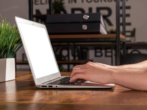Ręce pracują na klawiaturze laptopa przy biurku, pisząc pracę
