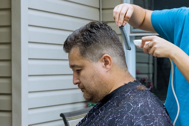 Ręce profesjonalnego fryzjera z nożyczkami i grzebieniem czeszą włosy męskiej fryzury dla klienta u mężczyzny
