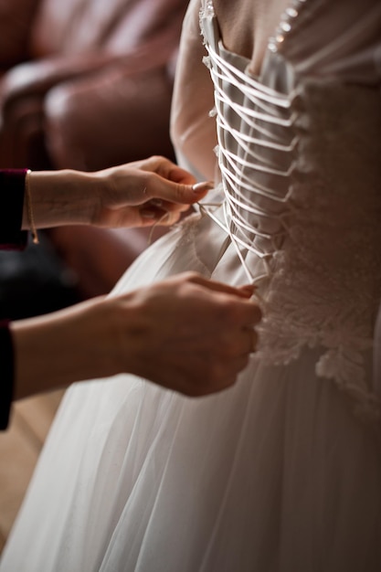 Ręce przyjaciółki zawiązują sznurowadła w sukience panny młodej 4044