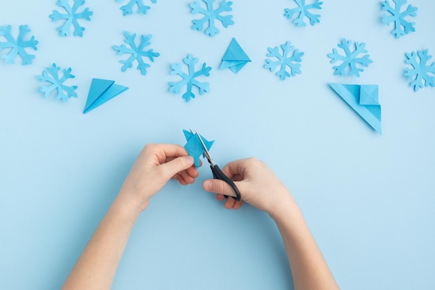 Zdjęcie ręce robiące papierowe płatki śniegu na niebieskich rękach dziecka wysokiej jakości zdjęcie