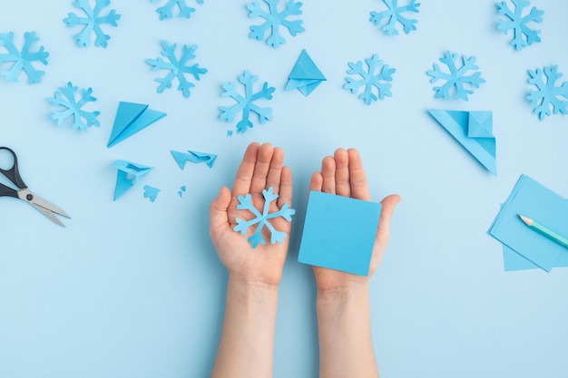 Zdjęcie ręce robiące papierowe płatki śniegu na niebieskich rękach dziecka wysokiej jakości zdjęcie