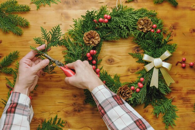 Ręce robiące świąteczny wieniec DIY wystrój domu na ferie zimowe