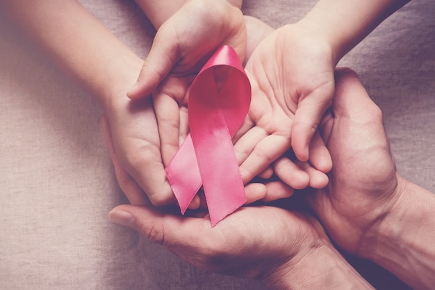 Ręce rodzinne trzymające różową wstążkę, świadomość raka piersi
