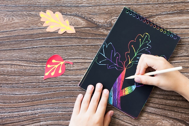 Zdjęcie ręce rysowanie kolorowych liści na notebooku