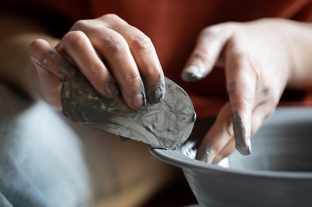 Zdjęcie ręce rzemieślnicze kobieta kształtująca naczynie gliniane za pomocą skrobaka podczas produkcji naczyń autorskich na sprzedaż