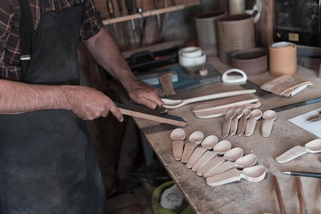 Ręce rzeźbienie łyżką z drewna, praca z dłutem z bliska. Warsztat drewniany. Proces robienia drewnianej łyżki. Zdjęcie wysokiej jakości