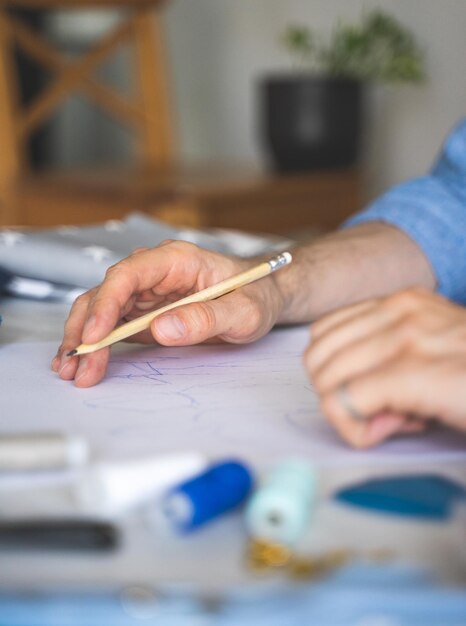 Ręce samouka projektanta są na jego szkicu Ręka z ołówkiem Projektant DIY rysuje szkic do nowego projektu kostiumu Z bliska selektywny styl życia