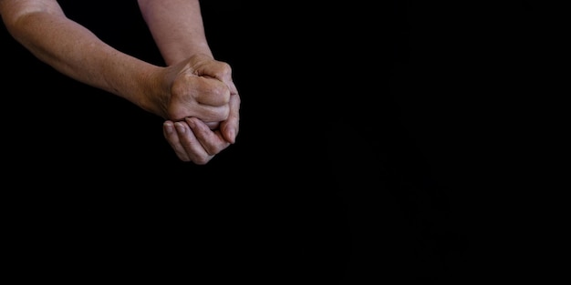 Ręce starszej kobiety w zmarszczkach na czarnym tle zbliżenia
