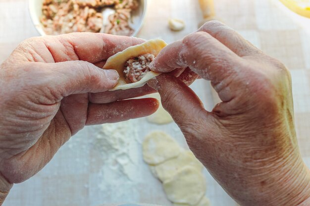 Ręce starszej pani robią pierogi