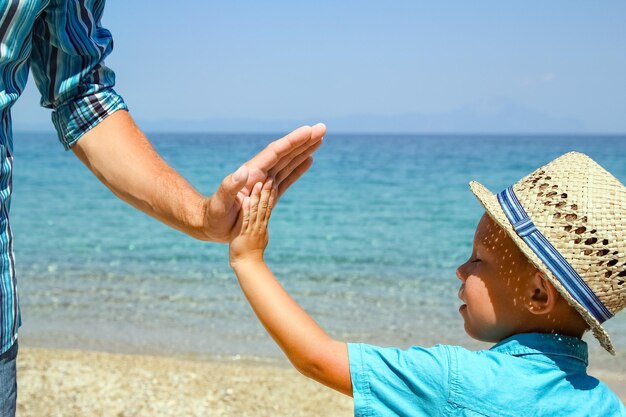 Ręce szczęśliwego rodzica i dziecka nad morzem w podróży natury