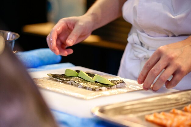 Ręce szefa kuchni przygotowujące japońskie jedzenie szef kuchni robiący sushi przygotowujący rolkę Maki Sushi