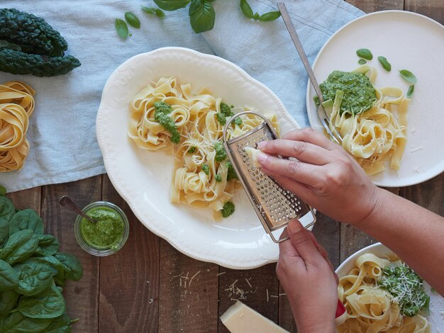 Zdjęcie ręce szorujące ser parmesan na talerzu tagliatelle