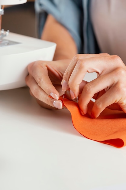 Zdjęcie ręce szycie z bliska pomarańczowej tkaniny