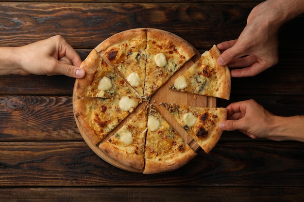 Ręce trzymać plastry smacznej pizzy z serem, widok z góry