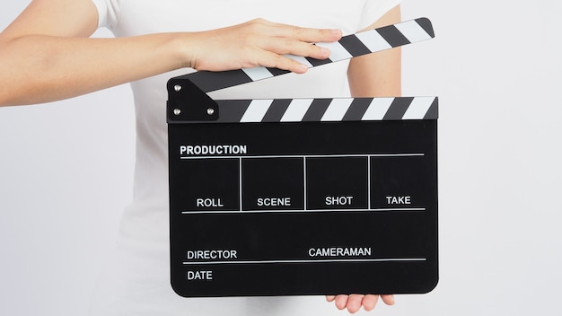 Ręce trzymają czarną klapkę lub klapkę filmową. wykorzystuje się go w produkcji wideo, filmie, przemyśle kinowym na białym tle.