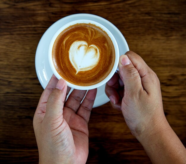 Ręce, trzymając kubek kawy serca