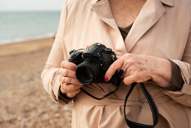 Zdjęcie ręce trzymające aparat fotograficzny nad morzem