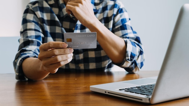Ręce trzymające kartę kredytową i używające laptopa Zakupy online
