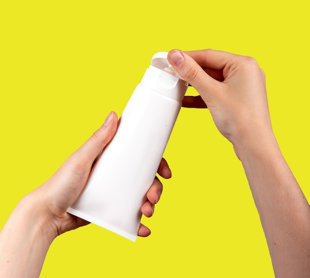 Ręce trzymające kremową makietę tubki makieta pustego produktu kosmetycznego izolowane na białej pokrywie otwierającej