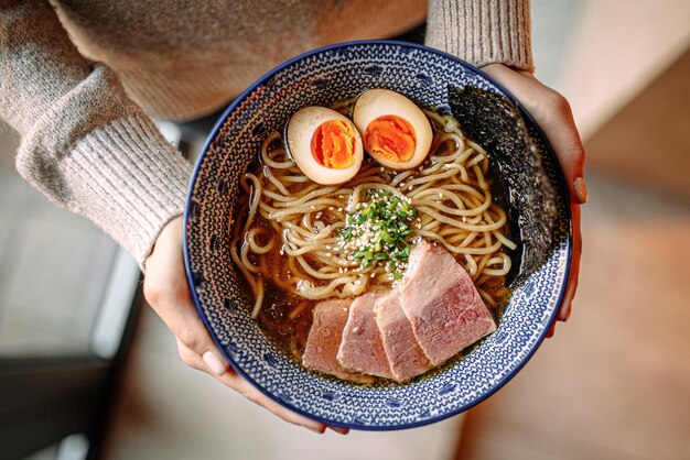 Zdjęcie ręce trzymające miskę japońskiej zupy z makaronem ramen