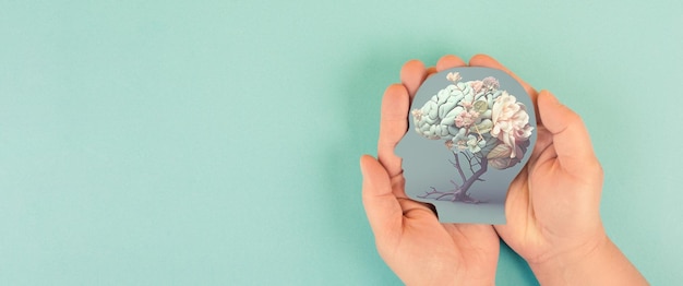 Ręce trzymające papierową głowę, ludzki mózg z kwiatami, samoopiekę i koncepcję zdrowia psychicznego, pozytywne